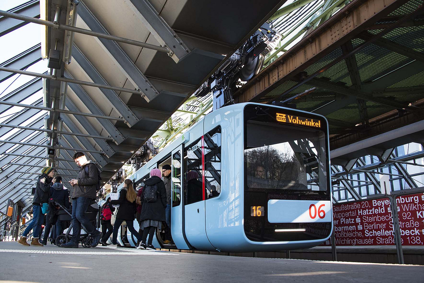 Eine Schwebebahn steht an der Station Ohligsmühle, Menschen steigen ein und aus