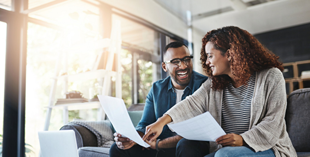 Ein lächelndes Paar lesen die Briefe im Wohnzimmer