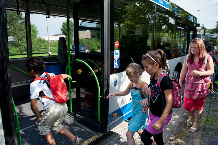 Kinder steigen in einen Bus ein.