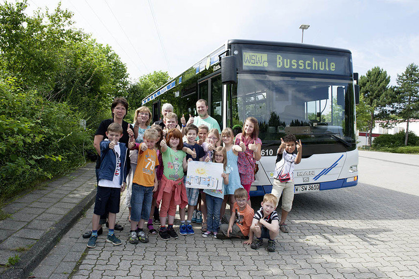 Eine Gruppe Kinder steht vor einem Bus.