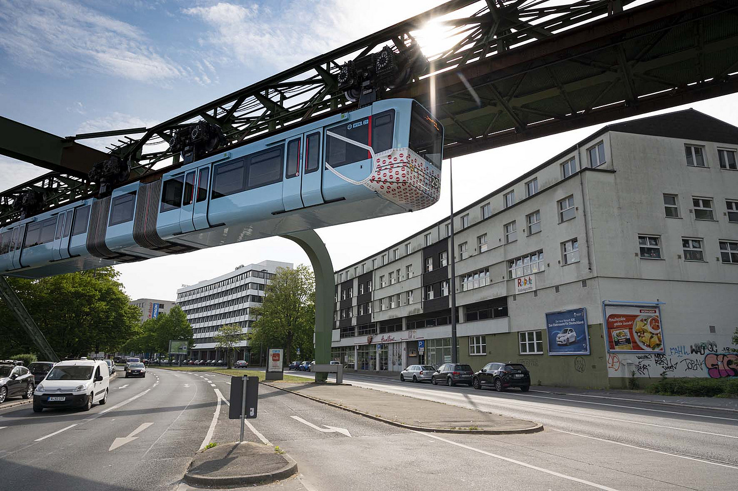 Eine Schwebebahn fährt mit einem Aufdruck, der aussieht, als würde sie eine Mundschutzmaske tragen