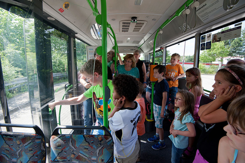 Eine Gruppe Kinder versucht im Bus, die Tür mit der Hand zu öffnen.
