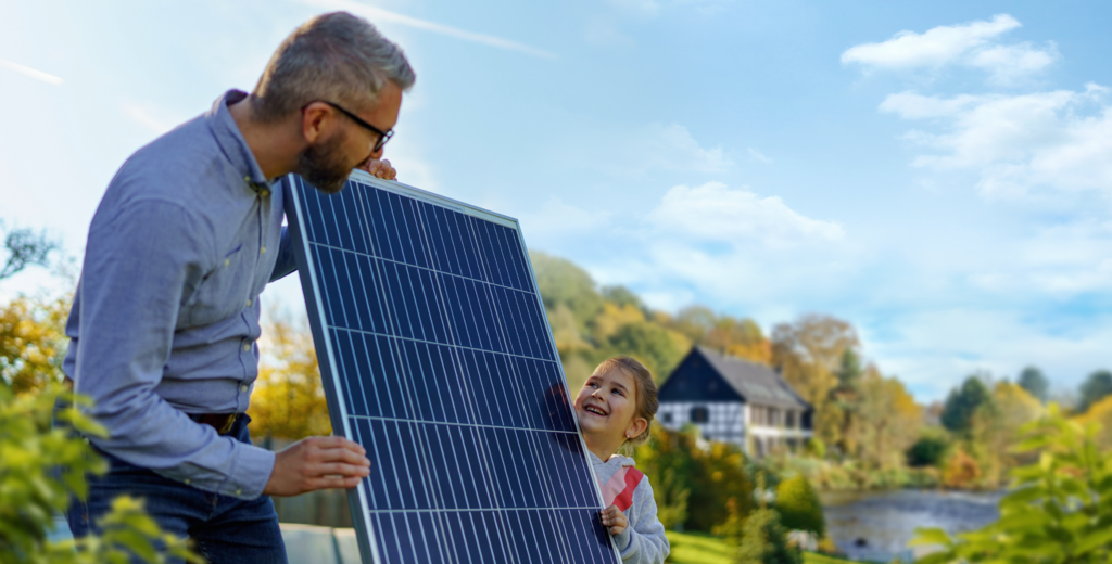 Mann und Tochter halten eine Photovoltaik-Anlage